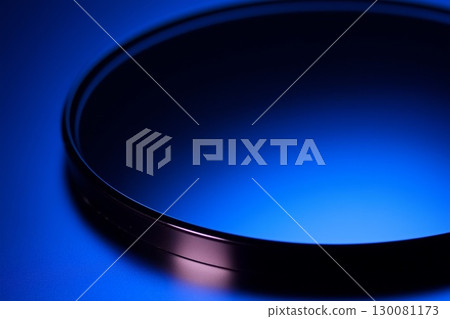 Scratched glass surface reflects dark blue lights in realistic studio setting 130081173