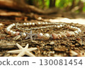 Elegant seashell bracelet adorned with pearls and coral fragments on a sandy beach 130081454