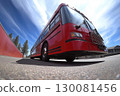 Bright red bus parked under a blue sky with wispy clouds at a roadside location 130081456
