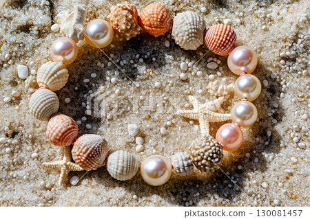 Elegant bracelet made of pearls and seashells resting on a sandy beach in sunlight 130081457
