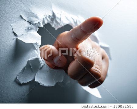 A finger breaking through white paper 130081593