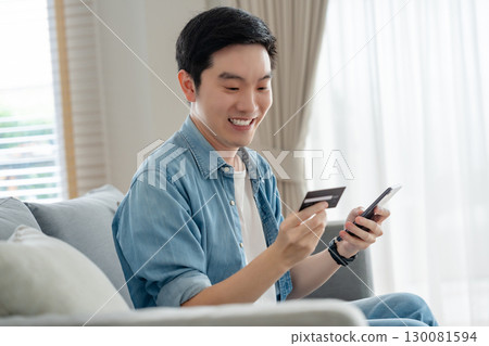 Young asian man sitting on sofa in living room Young asian man sitting on sofa in living room 130081594