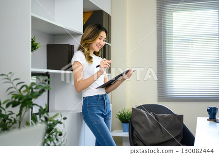 Cheerful young entrepreneur reviewing documents while working in modern workspace 130082444