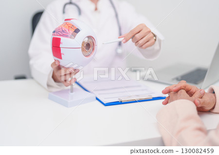 Elderly Patient consulting Doctor to Eye disease, Senior Medical Diagnosis. Anatomy Eye model for Cataract, Glaucoma, Age Related Macular Degeneration, Diabetic Retinopathy, Vitreous, health concept 130082459