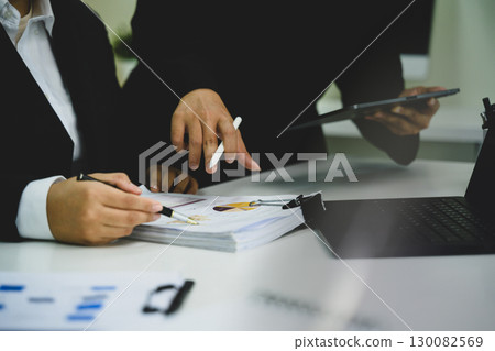 Business colleagues reviewing financial reports and charts during meeting 130082569
