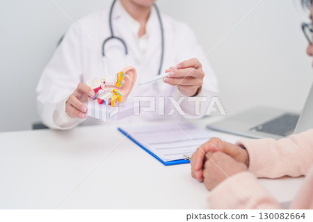 Elderly Patient consulting Doctor to Ear disease. Senior Health Medical Diagnosis. Anatomy Ear model for Atresia, Otitis Media, Pertorated Eardrum, Meniere syndrome, otolaryngologist, Hearing Loss 130082664