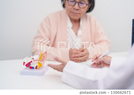 Elderly Patient consulting Doctor to Ear disease. Senior Health Medical Diagnosis. Anatomy Ear model for Atresia, Otitis Media, Pertorated Eardrum, Meniere syndrome, otolaryngologist, Hearing Loss 130082671