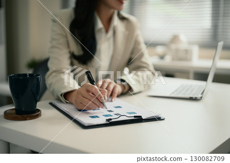 Close up of businesswoman analyzing documents with financial data 130082709