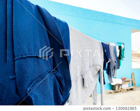 Clothes Drying on a Rope Against Blue Wall Outdoors 130082865