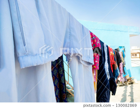 Clothes Drying on a Rope Against Blue Wall Outdoors 130082869