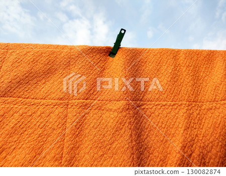 Orange Quilted Fabric Drying with Clothespin Orange Quilted Fabric Drying with Clothespin 130082874