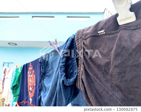 Clothes Drying on a Rope Against Blue Wall Outdoors Clothes Drying on a Rope Against Blue Wall Outdoors 130082875