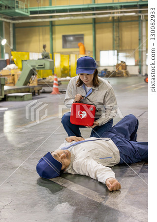 A woman provides medical assistance to a worker who collapsed at a factory 130082933