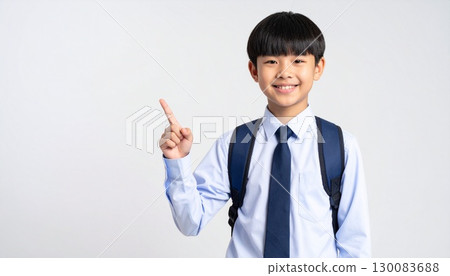 一名小學生背著書包，微笑著指著 130083688