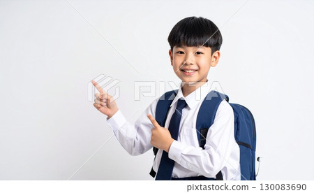 一名小學生背著書包，微笑著指著 130083690