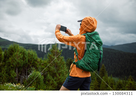 Hiking woman use smartphone taking picture on high altitude forest mountain top 130084311