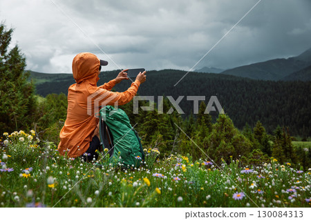 Hiking woman use smartphone taking picture on high altitude forest mountain top 130084313