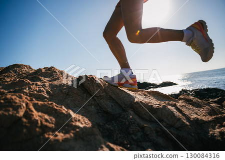 Runner legs running on sunrise seaside rocks Runner legs running on sunrise seaside rocks 130084316