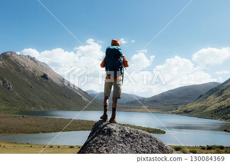 Woman backpacker hiking on high altitude mountain top,with a lake in the distance Woman backpacker hiking on high altitude mountain top,with a lake in the distance 130084369