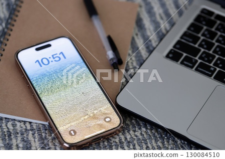 地毯上放置著一台筆記型電腦、一部智慧型手機和一些書寫工具 130084510