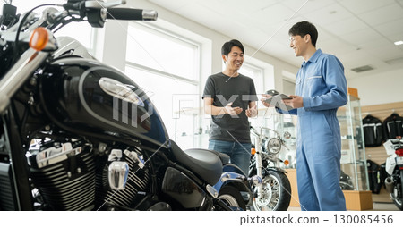 一位顧客和一位銷售人員在摩托車店裡談判 130085456