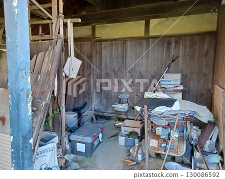 一座關閉的農舍的木製穀倉，在清理之前，仍然堆滿了農業設備和工具 130086592
