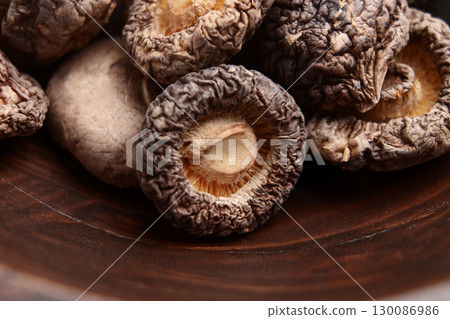 Raw dehydrated shiitake mushrooms in wooden rustic bowl. Dried foods 130086986