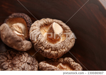 Dried edible shiitake mushrooms in a rustic wooden bowl.  130086987