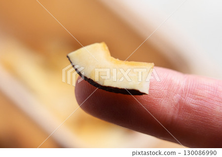 Dried coconut slice on finger. Vitamin nutritious chips 130086990