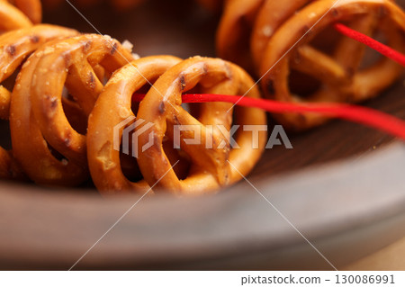 Salty pretzels crackers with salt crystals strung on a red rope in wooden bowl 130086991
