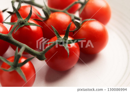 Freshly picked sprigs of ripe red cherry tomatoes on ceramic plate. Macro shot.  130086994