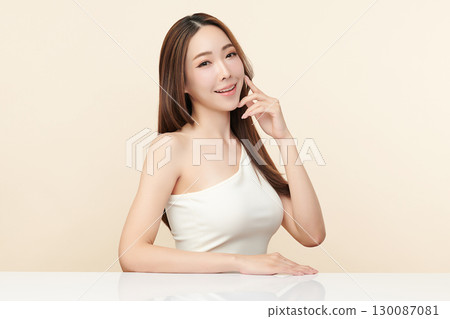 A beautiful young Asian woman with clean, fresh skin against a beige background. Skincare, facial treatment, cosmetology, beauty, and spa. An elegant portrait of an Asian woman. A beautiful young Asian woman with clean, fresh skin against a beige background. Skincare, facial treatment, cosmetology, beauty, and spa. An elegant portrait of an Asian woman. 130087081