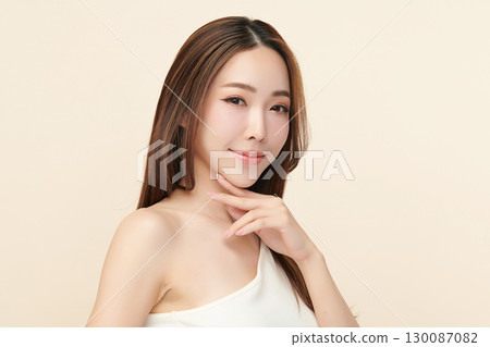 A beautiful young Asian woman with clean, fresh skin against a beige background. Skincare, facial treatment, cosmetology, beauty, and spa. An elegant portrait of an Asian woman. A beautiful young Asian woman with clean, fresh skin against a beige background. Skincare, facial treatment, cosmetology, beauty, and spa. An elegant portrait of an Asian woman. 130087082