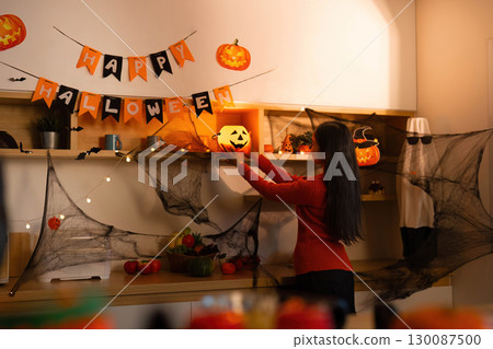 Halloween Setup. Woman placing pumpkin decoration on festive display. Halloween Setup. Woman placing pumpkin decoration on festive display. 130087500