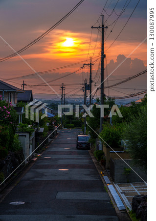 Late summer: A golden sunset peeking through the clouds, enveloping the cityscape in the glow of the setting sun Late summer: A golden sunset peeking through the clouds, enveloping the cityscape in the glow of the setting sun 130087995