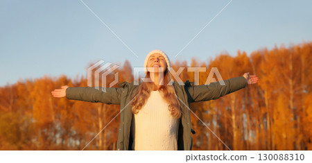 Happy young woman in autumn park, joyful girl enjoying warm sunny weather, nature 130088310