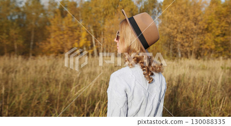 Stylish young woman in autumn park, looking at landscape, wear brown hat outdoors Stylish young woman in autumn park, looking at landscape, wear brown hat outdoors 130088335