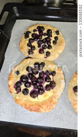 Homemade baked buns with cottage cheese and fresh blueberries on parchment paper. Concept of rustic baking, comfort food and sweet homemade dessert 130088582