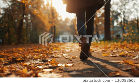 The feet of a woman walking along a tree-lined path in autumn 130088605