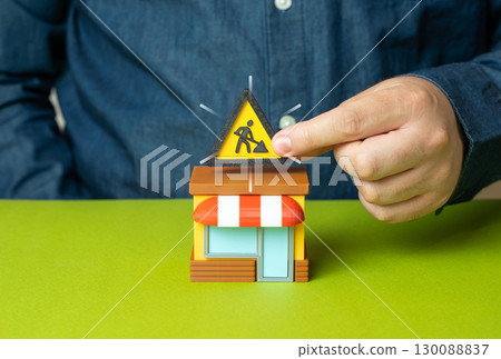 Men holding a sign for renovation work above a store. Business expansion. Company reorganization. Modernization, growth strategy, new opportunities Men holding a sign for renovation work above a store. Business expansion. Company reorganization. Modernization, growth strategy, new opportunities 130088837