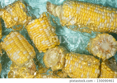 Fresh corn cobs splashing in water top view. Fresh corn cobs splashing in water top view. 130090461