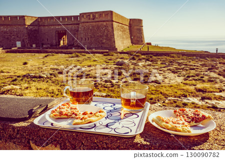 Tea mug and pizza slices on plate, outdoors Tea mug and pizza slices on plate, outdoors 130090782
