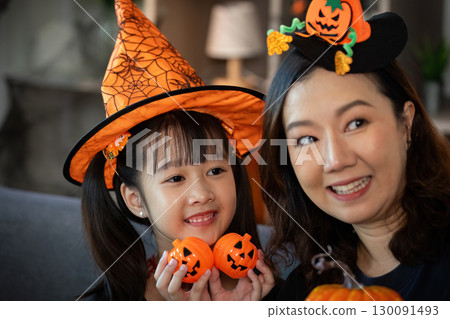 Halloween Spirit. Smiling mother and daughter showcasing festive pumpkin decorations. 130091493