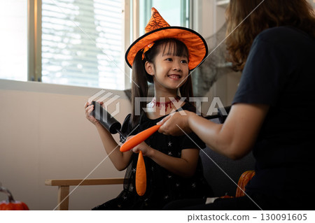 Halloween Joy. A girl smiles while holding Halloween props and preparing for the celebration. Halloween Joy. A girl smiles while holding Halloween props and preparing for the celebration. 130091605
