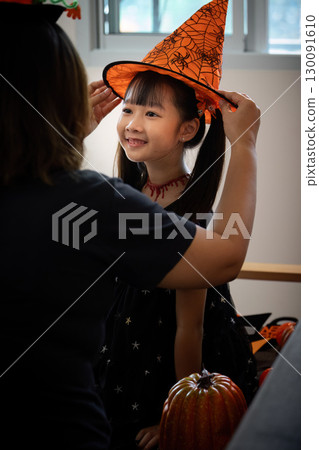 Halloween Fun. A mother helps her daughter adjust a festive witch hat for Halloween. Halloween Fun. A mother helps her daughter adjust a festive witch hat for Halloween. 130091610