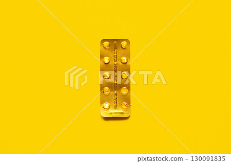 Used golden blister pack on yellow background. 130091835