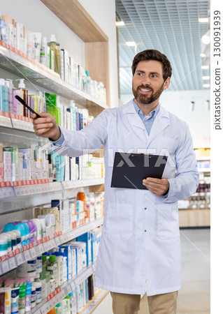 Bearded male pharmacist showing medicine on the shelf in the pharmacy 130091939