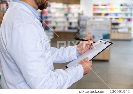 Close up picture of a man in lab coat making notes 130091943