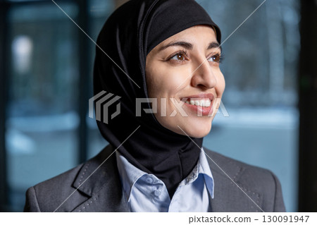 Waist up of a young woman in hijab looking contented 130091947