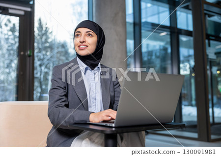 Muslim businesswoman in hijab working on laptop and looking involved Muslim businesswoman in hijab working on laptop and looking involved 130091981